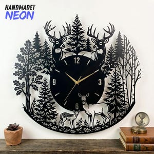Puede incluir: Reloj de pared de metal negro con una escena de bosque con ciervos y árboles. La esfera del reloj tiene manecillas doradas y los números 12, 3, 6 y 9. El texto "HANDMADET NEON" está en la esquina superior izquierda.