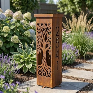Puede incluir: Una columna de jardín rectangular y alta de metal color óxido, con un diseño de árbol cortado con láser en el panel frontal y los números de casa 2541 cortados verticalmente en el panel lateral, sobre una superficie de piedra plana.