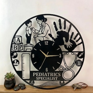 May include: Black metal wall clock with a pediatrician theme. The clock features a doctor examining a child, a stethoscope, and the words "Pediatrics Specialist." The clock also includes a handprint and a clock face.