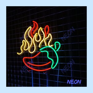 May include: A neon sign featuring a chili pepper with flames. The chili pepper is outlined in green and red, with yellow flames above. The word "NEON" is written in blue in the bottom right corner. The background is a black grid.