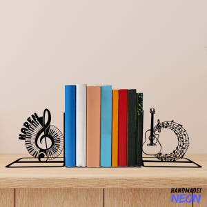 May include: Black metal bookends featuring a treble clef and piano keys on one side and a guitar with musical notes on the other. The bookends are holding up a row of colorful books. The bookends are personalized with the name "KAREN".