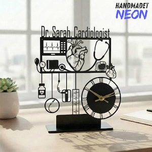 May include: Black laser-cut desk clock featuring a cardiologist theme. The clock includes a heart, stethoscope, and medical equipment. The clock face has Roman numerals and gold-colored hands. The text "Dr. Sarah, Cardiologist" is displayed at the top.