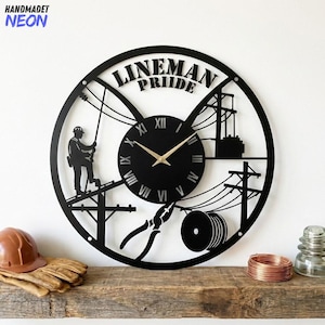 May include: Black metal wall clock with a lineman theme. The clock features a silhouette of a lineman, power lines, tools, and the words "Lineman Pride." The clock hands are gold-colored.