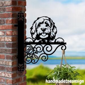 Puede incluir: Letrero de pared de metal negro con una silueta de cabeza de perro asomándose por la parte superior. El letrero tiene un diseño decorativo de volutas y un gancho para colgar.