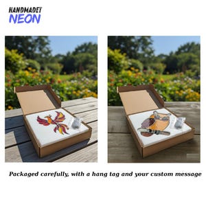 May include: Two square glass art pieces in cardboard boxes. One features a colorful phoenix design, the other an owl wearing glasses. The boxes are on a wooden surface with a blurred background of trees and flowers. The text "HANDMADET NEON" is visible.