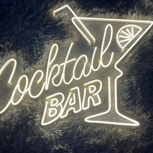 K&ouml;nnte beinhalten: Wei&szlig;es Neon-Schild mit den Worten "Cocktail Bar" und einem Martini-Glas mit einer Zitronenscheibe.