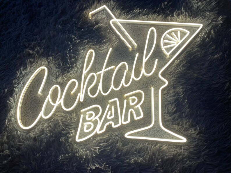 K&ouml;nnte beinhalten: Wei&szlig;es Neon-Schild mit den Worten "Cocktail Bar" und einem Martini-Glas mit einer Zitronenscheibe.