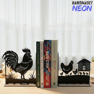 May include: Black metal bookends featuring a rooster and hen design. The rooster bookend shows a detailed silhouette of a rooster standing in grass. The hen bookend depicts a hen, chicks, and a small house. The word "HANDMADET NEON" is in the top right corner.