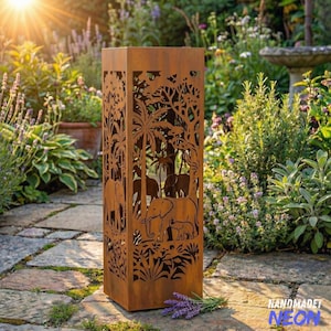 May include: A rectangular, weathered metal garden lantern with cut-out elephant and jungle designs. The brown lantern stands on a stone path, surrounded by lush greenery and flowers. The text "HANDMADET NEON" is visible.