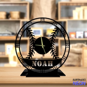 May include: Black metal desk clock with a baseball design and the name "NOAH" inscribed on the face. The clock has a black background and gold hands.
