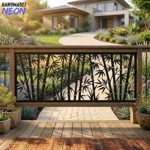 May include: A rectangular black metal privacy screen featuring a laser-cut bamboo stalk and leaf pattern. The panel is framed by a wooden railing and is positioned on a wooden deck, with a blurred view of a house and garden in the background.