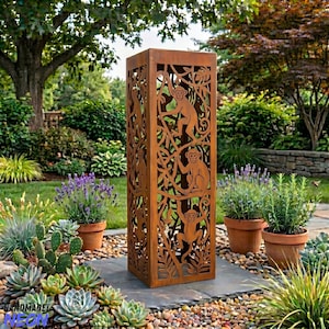 May include: A tall, rectangular, rusted metal garden sculpture with cut-out monkey and foliage designs. The sculpture stands on a stone path in a garden setting, surrounded by plants and flowers. The sculpture is a decorative outdoor accent.