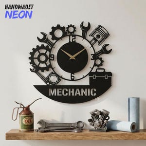 Könnte beinhalten: Schwarze Wanduhr im Mechaniker-Stil mit Zahnrädern, Schraubenschlüsseln und einem Kolben-Design. Das Zifferblatt hat goldfarbene Zeiger und das Wort "MECHANIC" ist darunter abgebildet. Die Worte "HANDMADET NEON" befinden sich in der oberen linken Ecke. Unterhalb befindet sich ein Regal mit Werkzeugen und einem kleinen Motormodell.