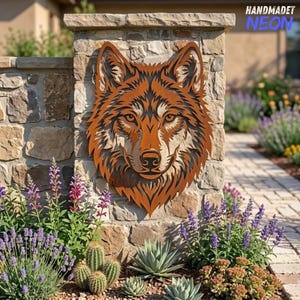May include: A rust-coloured metal wall art piece shaped like a wolf head with intricate cut-out details. The wolf features pointed ears, focused eyes, and a textured fur pattern. The metal art is mounted on a stone pillar.