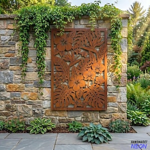 May include: A rectangular, rust-colored metal wall art piece featuring a tropical floral design. The artwork is mounted on a stone wall and includes cut-out images of hibiscus, orchids, and large leaves. Green plants and vines surround the artwork.