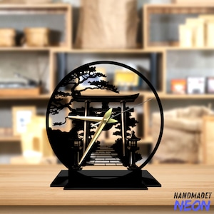 May include: Black metal clock featuring a silhouette of a Japanese torii gate and a tree. The clock hands are gold.