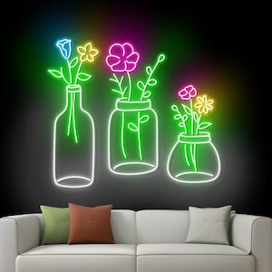 May include: Neon sign depicting three vases with flowers. The vases are outlined in white and the flowers are in various colors, including pink, blue, yellow, and green. The background is black.