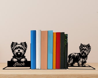 May include: Black metal bookends featuring a Yorkshire Terrier silhouette on each side. The bookends are holding up a stack of books. The left bookend has the name "Jack" inscribed on it.