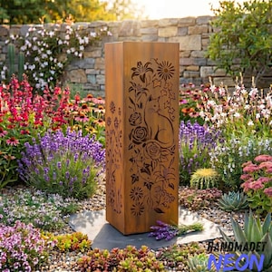 Puede incluir: Una jardinera alta y rectangular de metal envejecido con un diseño de gato y flores recortado en los laterales. La jardinera está rodeada de flores y vegetación coloridas. El texto "HANDMADET NEON" es visible en la parte inferior derecha.