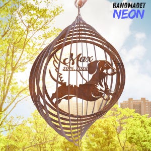 May include: A brown metal wind spinner with a dachshund silhouette inside a spiral cage design. The name "Max" and the years "2015-2024" are included. The words "HANDMADET NEON" are in the upper right corner.