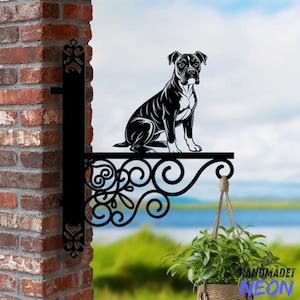 May include: Black metal wall mount with a silhouette of a boxer dog. The mount has a decorative scroll design and a hanging hook. The mount is attached to a brick wall.