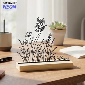 Peut inclure: Une décoration en métal noir représentant un papillon et des fleurs sur une base en bois. Le mot "Williams" est écrit sur la base. Les mots "HANDMADET NEON" sont dans le coin supérieur gauche.