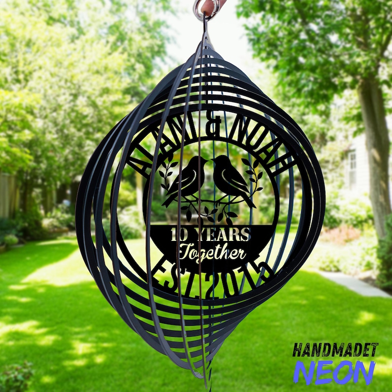 Puede incluir: Molinillo de viento de metal negro con dise&ntilde;o en espiral. El centro presenta dos p&aacute;jaros posados en una rama, con el texto "10 YEARS Together EST 2014" y los nombres "ALAN & NOAH". Un adorno decorativo de jard&iacute;n.