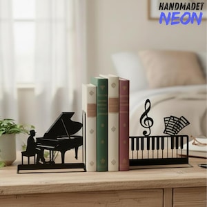 May include: Black metal bookends with a piano theme. One depicts a pianist at a grand piano, the other a piano keyboard with musical notes and a treble clef. The text "HANDMADET NEON" is visible.