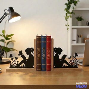 May include: A wooden bookend set with a black silhouette design of a girl reading, butterflies, and flowers. The bookends hold three books with the word "BOOKS" on the spines. The bookends are on a wooden desk.