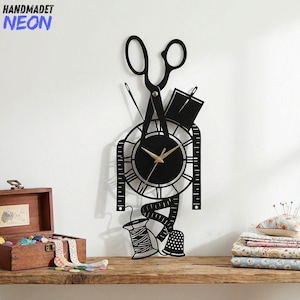 May include: Black wall clock with a sewing theme, featuring scissors, a measuring tape, and a spool of thread. The clock hands are gold. The text "HANDMADET NEON" is in the upper left corner. The clock is on a wooden shelf.