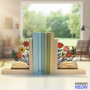 May include: Wooden bookends with laser-cut floral designs in orange, yellow, and pink. The bookends hold a row of colorful books. The base of the bookends has the text "HANDMADET NEON" in blue.