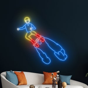 Könnte beinhalten: Neon-Schild, das eine Person auf einer Rakete mit blauen, gelben und roten Neonlichtern zeigt.