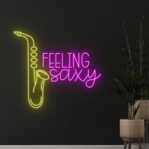 Puede incluir: Un letrero de neón con un saxofón amarillo y el texto "Feeling saxy" en rosa.