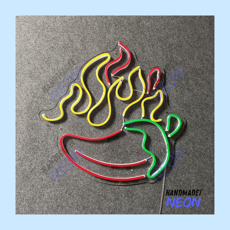 May include: A neon sign in the shape of a chili pepper with flames. The chili pepper is red and green, with yellow and red flames. The sign has the text "HANDMADET NEON" in blue.