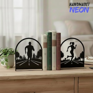 May include: Black metal bookends with running figures. One shows a man running on a road, the other a woman. The bookends are holding books. The text "HANDMADET NEON" is in the upper right corner.