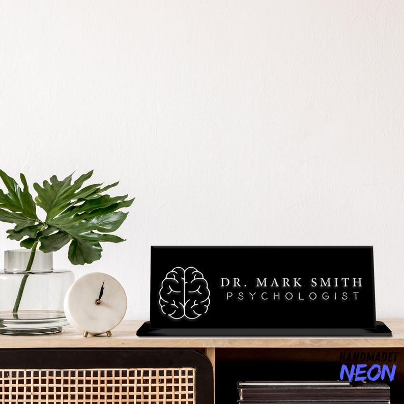 May include: Black desk sign with a white brain outline and the text "Dr. Mark Smith Psychologist" in white lettering.