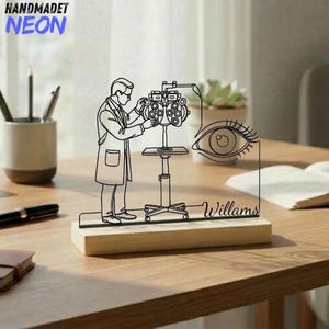 Könnte beinhalten: Eine schwarze Strichskulptur eines Augenarztes, der ein Auge mit einer Sehtafel untersucht, mit dem Namen "Williams" auf einem Holzsockel. Das Wort "HANDMADET NEON" befindet sich oben links.
