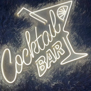 K&ouml;nnte beinhalten: Wei&szlig;es Neon-Schild mit den Worten "Cocktail Bar" und einem stilisierten Cocktailglas mit einer Zitronenscheibe.