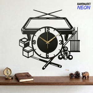 Könnte beinhalten: Schwarze Wanduhr mit Billard-Motiv. Die Uhr zeigt einen Billardtisch, Queues, Billardkugeln und ein Zifferblatt mit goldenen Zeigern. Der Text "HANDMADET NEON" befindet sich in der oberen rechten Ecke.
