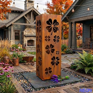 May include: A tall, rectangular, weathered metal garden sculpture with clover cutouts. The sculpture is a rusty brown color and stands on a stone base. The background includes a house, garden, and string lights.