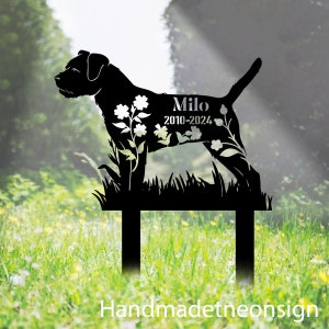 May include: Black metal silhouette of a dog with flowers and the text "Milo 2010-2024". The silhouette is mounted on a stake for placement in the ground.