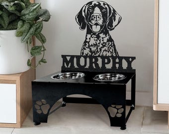 May include: Black metal dog bowl stand with two bowls, featuring a silhouette of a German Shorthaired Pointer dog and the name "Murphy".
