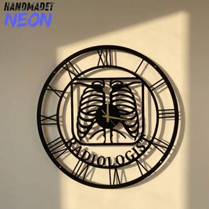 May include: A black circular wall clock featuring Roman numerals and a central cutout design of a human rib cage. The word RADIOLOGIST is inscribed at the bottom of the clock face. The clock has thin gold-colored hands at the center.