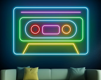 May include: A neon sign shaped like a cassette tape with rainbow colours. The sign is on a dark blue wall above a green sofa.