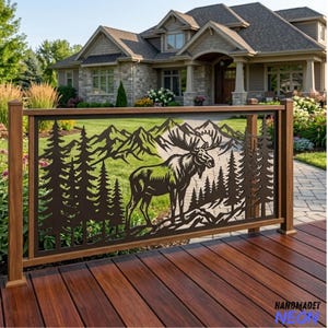 May include: A dark brown metal railing panel featuring a laser-cut design of a standing moose in the centre, surrounded by a forest of pine trees and a mountain range in the background. The panel is mounted between wooden posts on a deck.