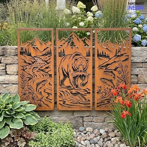May include: A set of three rectangular metal wall panels featuring a laser-cut design of a mountain landscape, a bear catching a fish, and a river scene with jumping fish. The panels have a rusted brown finish and intricate nature silhouettes.