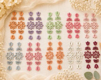 May include: A collection of colorful, floral-shaped earrings in various shades, including orange, purple, green, pink, and white. The earrings are arranged in rows, showcasing their intricate designs and diverse color palettes. The earrings are made of wood.