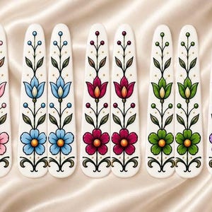 May include: Ten white hair clips arranged in five matching pairs, each featuring a vertical floral illustration in pink, blue, dark red, green, and purple. The designs include a central flower at the base with stems, leaves, and small berries.
