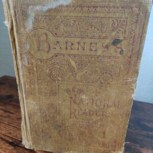 Puede incluir: Un libro vintage marrón y rojo con el título "Barnes' National Readers No. 1" en la portada.