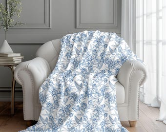 Manta decorativa azul con estampado botánico de rosas y golondrinas de estilo campestre francés.